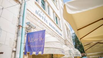 A hotel with a sign reading "HOTEL RESTAURANT" and a banner for "Astoria Bar Restaurant" below it.