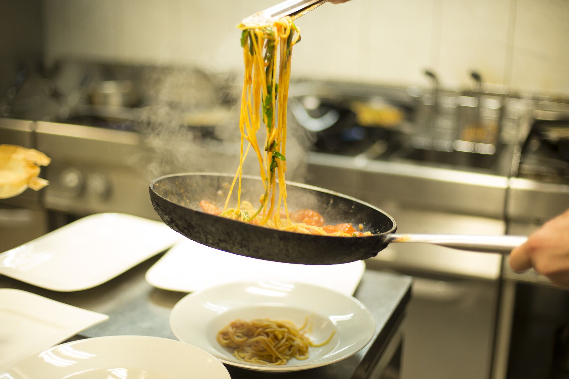 Una persona cocinando espagueti en una sartén.