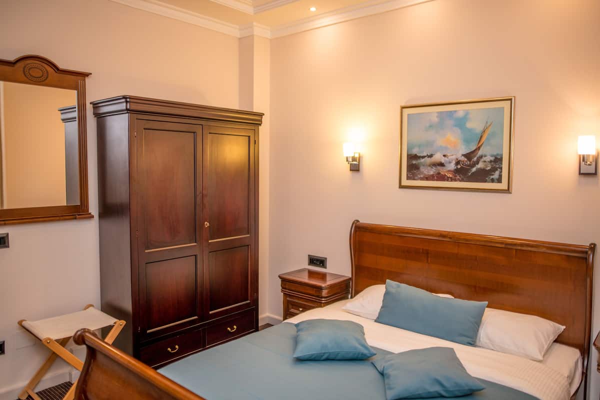 Un dormitorio con una cama de madera, una mesita de noche, un aparador y un cuadro en la pared.