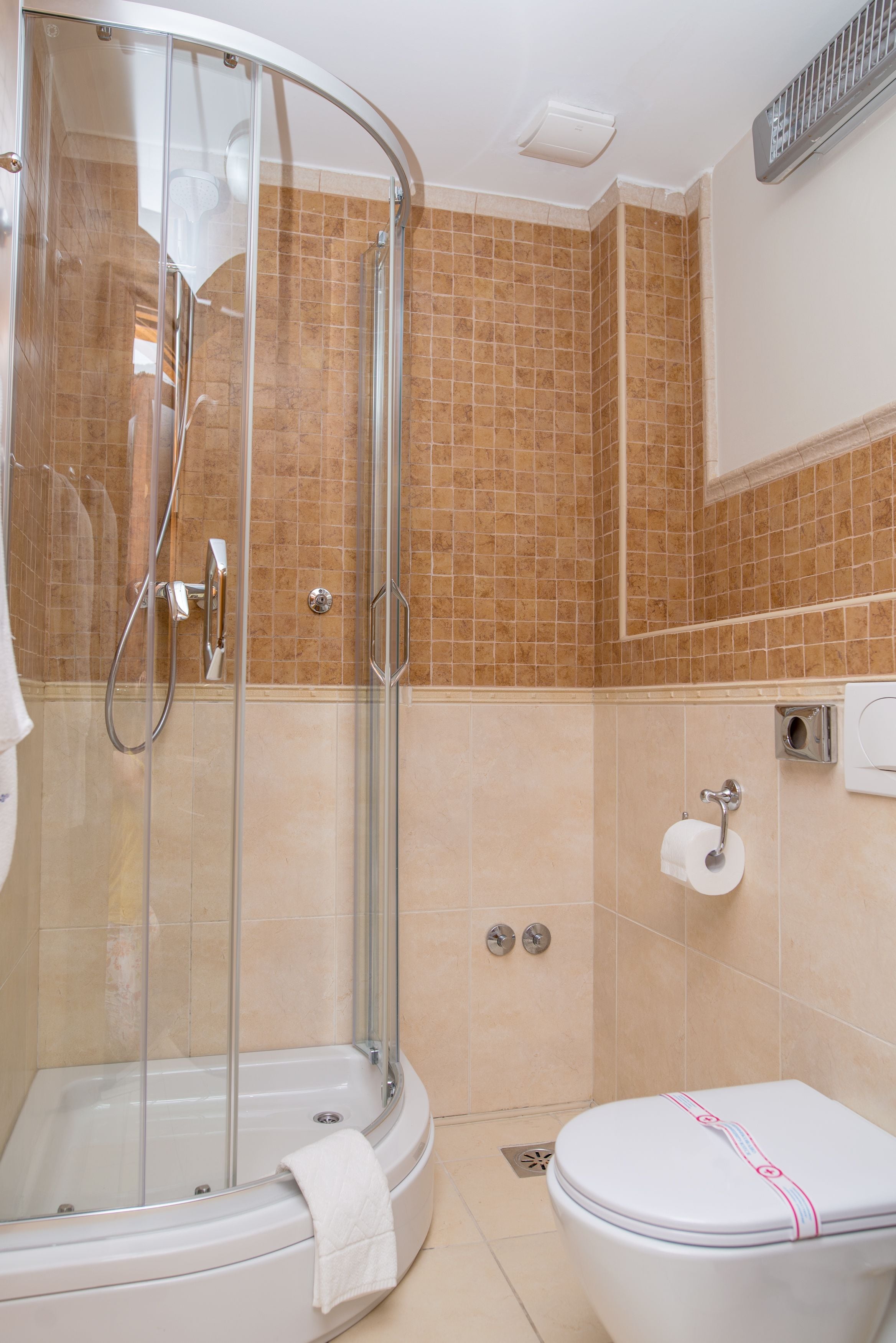 A bathroom with a glass-enclosed shower, a toilet, and a sink.