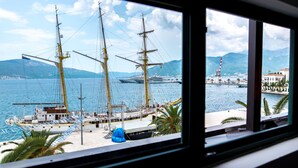 Vista de un puerto con altos barcos de vela y un crucero amarrado.