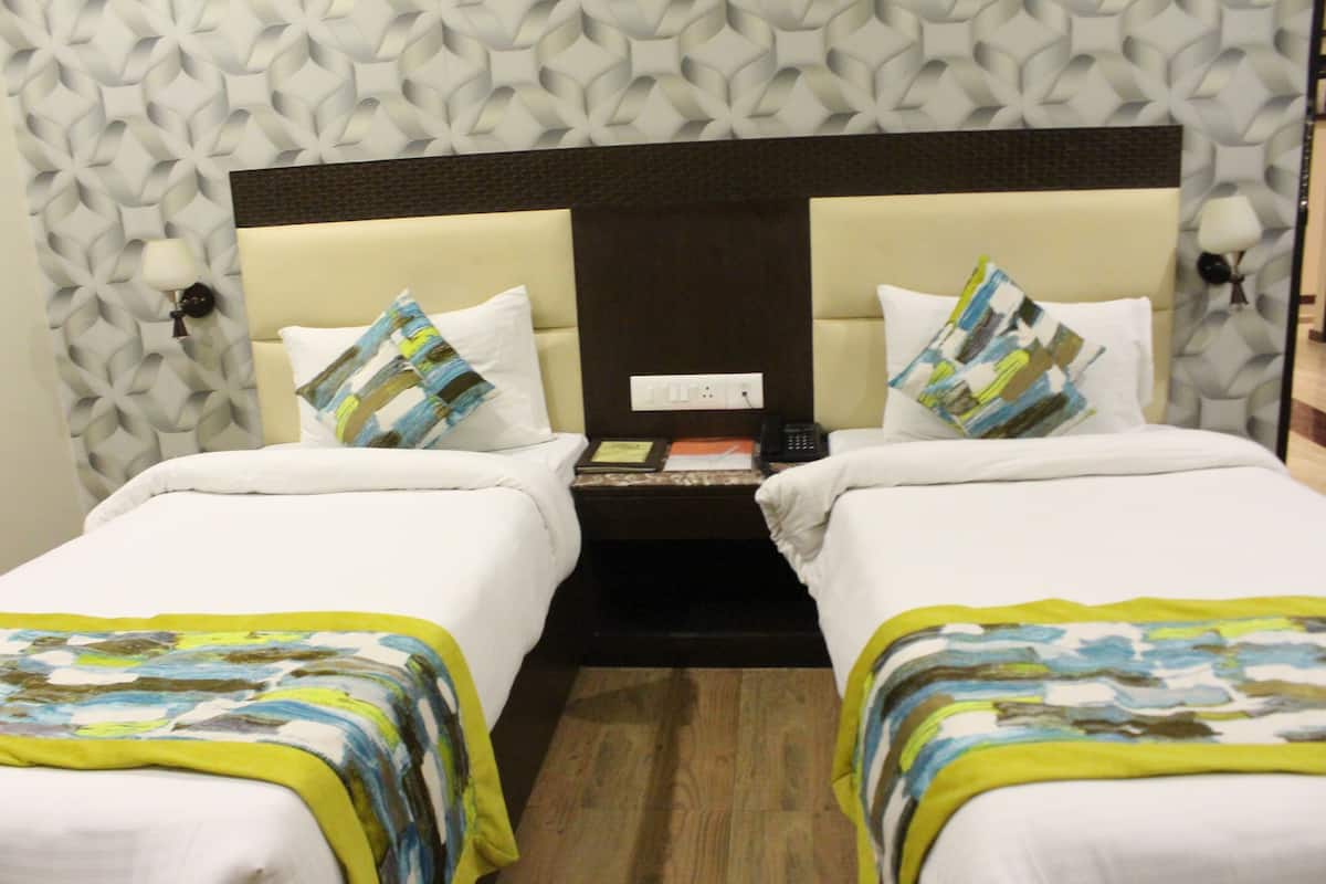 A hotel room with two beds, a nightstand, and a patterned wall.