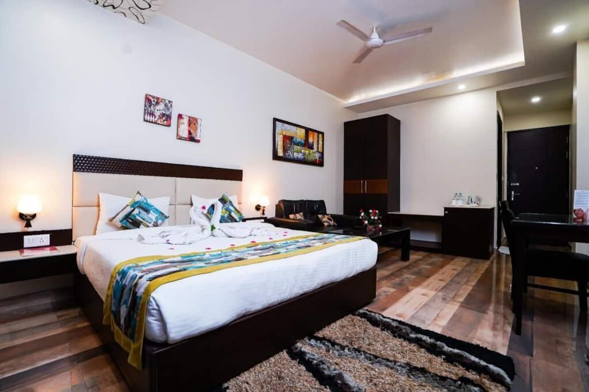 A hotel room with a bed, bedside tables, a desk, a chair, and artwork on the walls.
