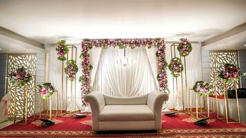 A stage with a sofa, draped curtains, and floral arrangements.