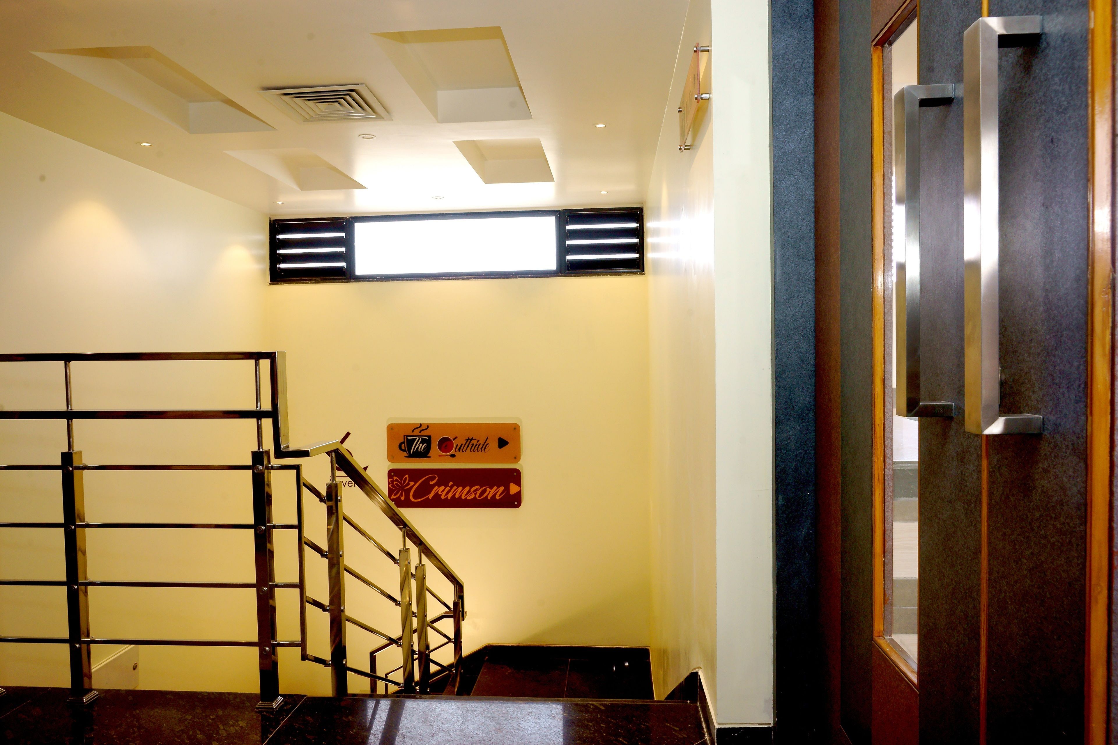 Un escalier avec une rampe en métal, une enseigne fixée au mur et une porte dotée d’une poignée.