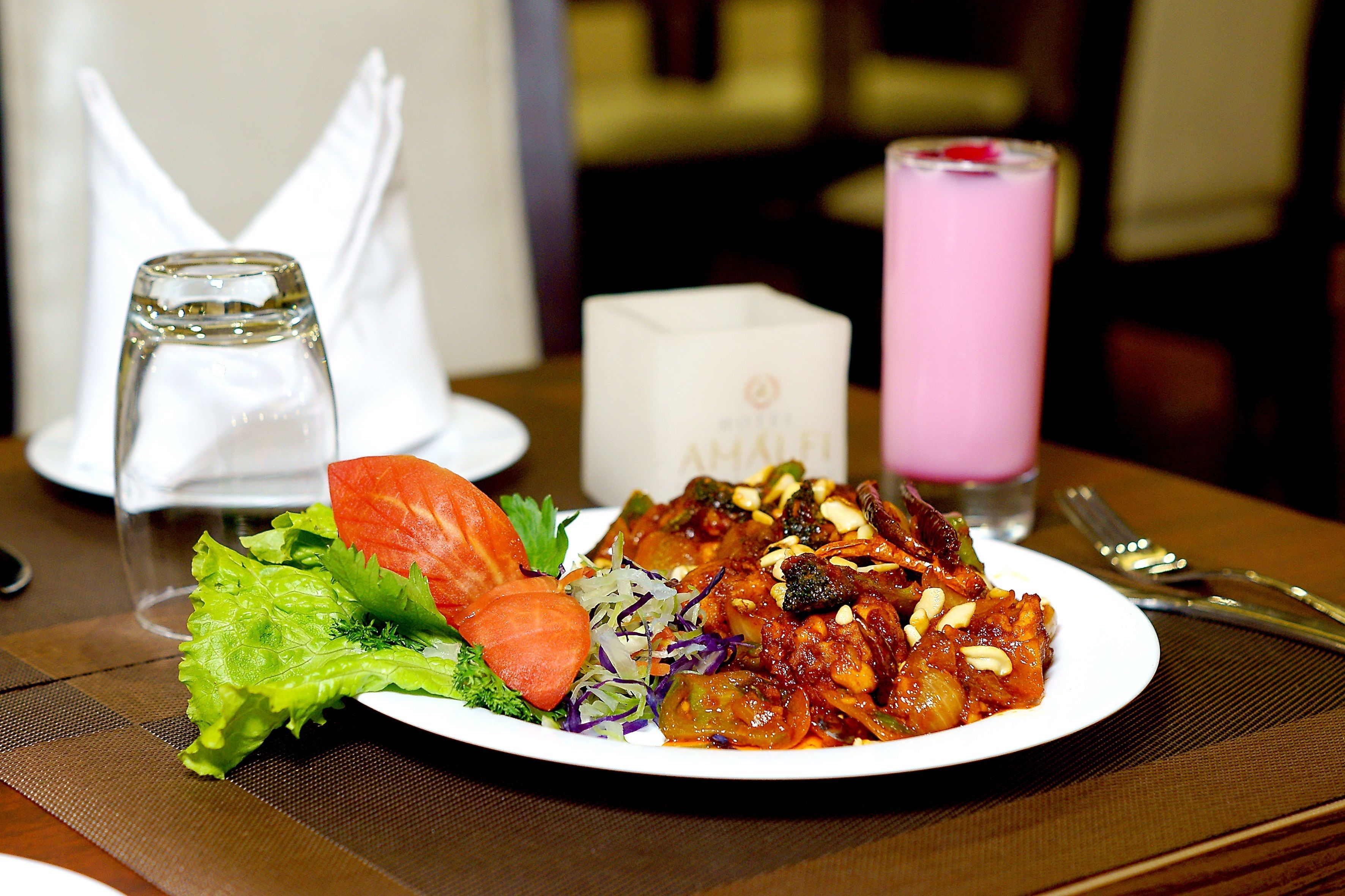 A plate of food with vegetables and a pink drink on a table.
