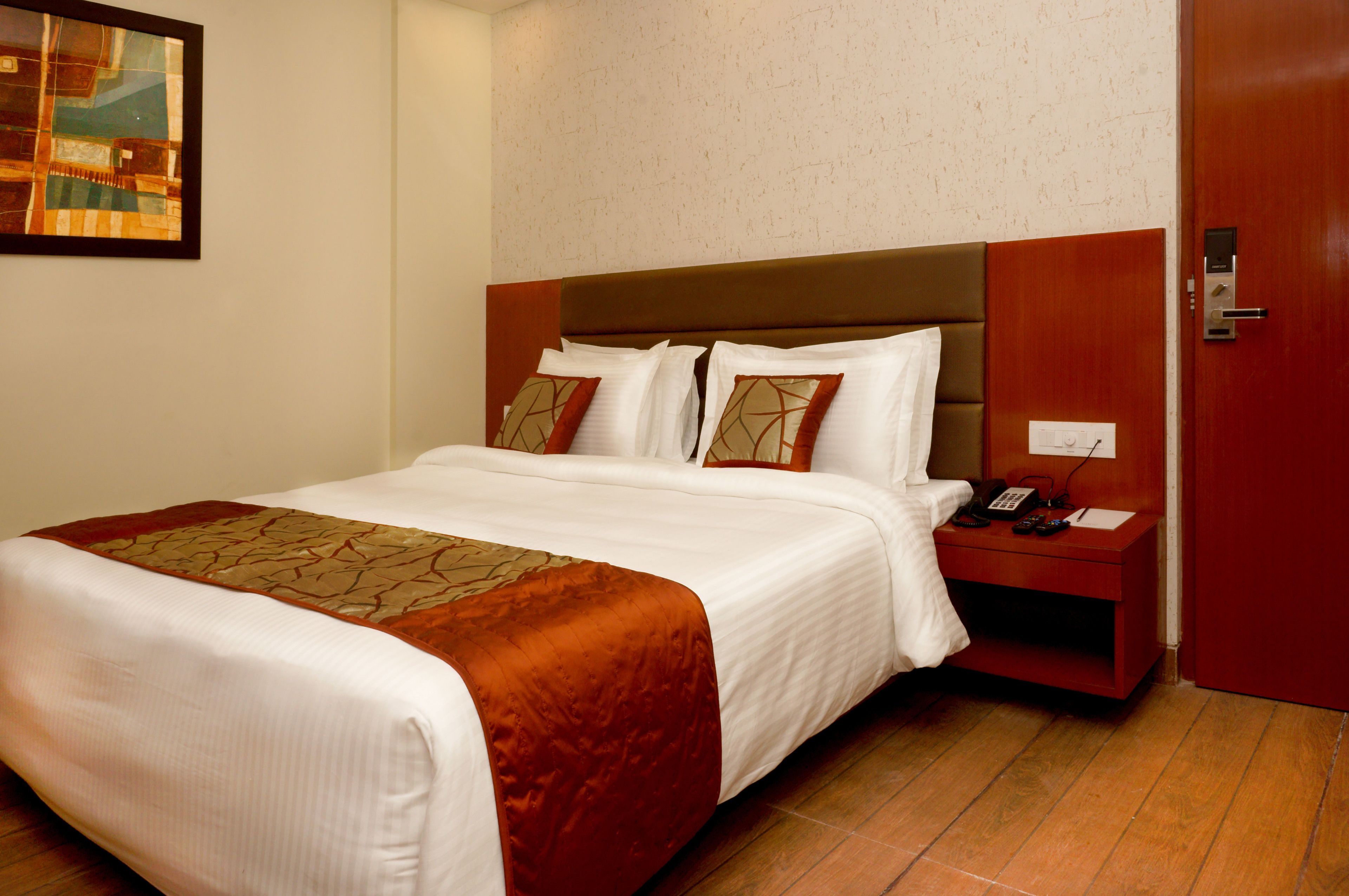 A hotel room with a large bed, a nightstand with a phone, and a door.