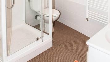 Ein Badezimmer mit einer Duschkabine, einer Toilette und einem weißen Waschbecken.