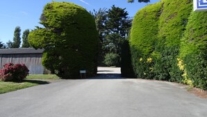 A paved road flanked by well-maintained hedges and a wooden fence. - Le Toul' Broch (Baden)
