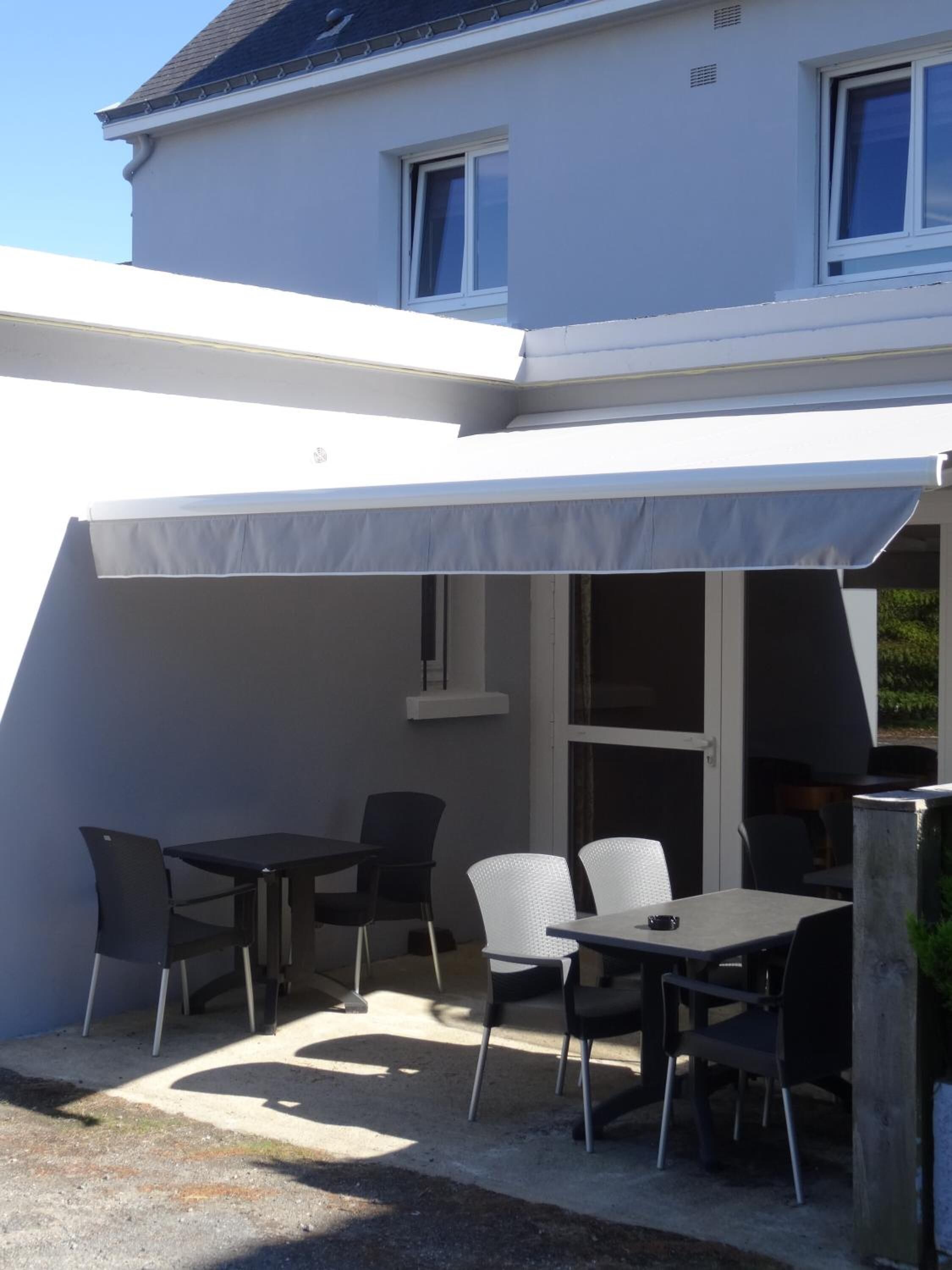 An outdoor patio area with a covered seating arrangement, including tables and chairs.