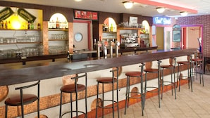 A bar area with stools, shelves of bottles, and a neon sign. - Le Toul' Broch (Baden)