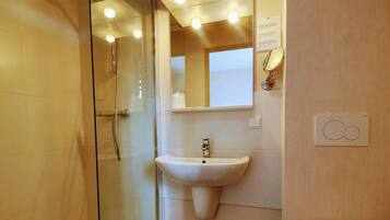 A bathroom with a glass shower enclosure, a sink, a toilet, and a mirror.