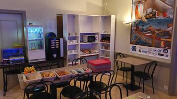 Un espace repas comprenant une table de buffet, des chaises, un réfrigérateur et une affiche accrochée au mur.