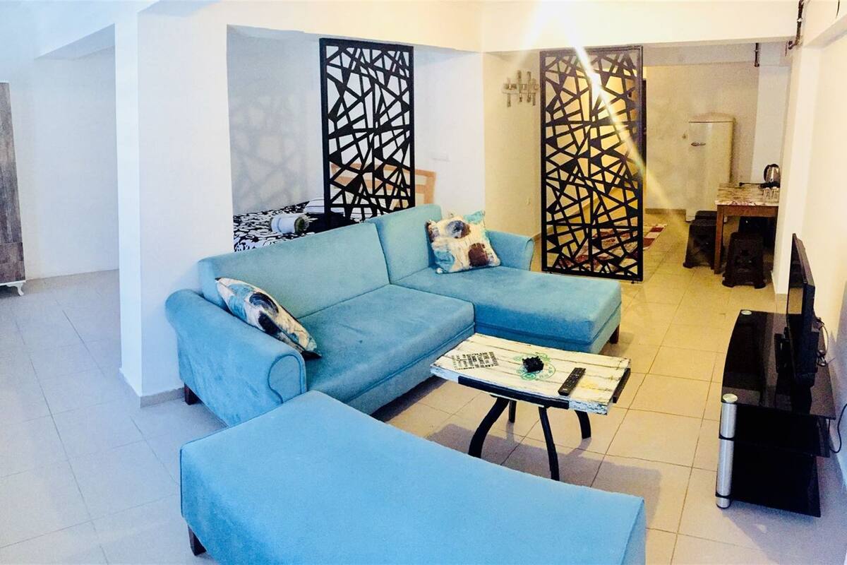 A living room with a blue sofa, a coffee table, and a decorative screen.