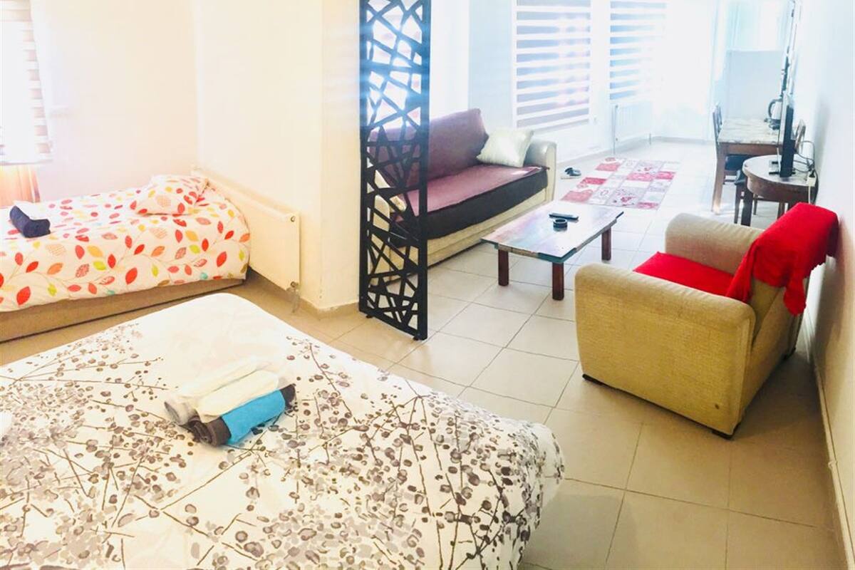 A living room with a sofa, a chair, a coffee table, and a bed with a patterned bedspread.