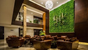 Um lobby moderno com sofás de couro, um jardim vertical verde e um lustre único.