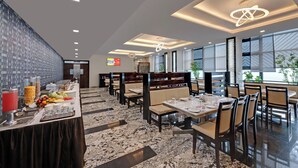 Um restaurante moderno com piso de mármore, cabines de madeira e um espaço para buffet com frutas e bebidas.