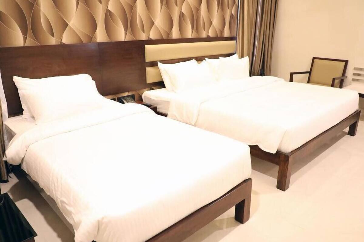 Une chambre d’hôtel avec deux lits, une tête de lit en bois et un décor mural texturé.