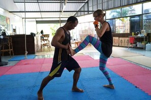 A martial arts training session in a spacious indoor area with a high ceiling and large windows.