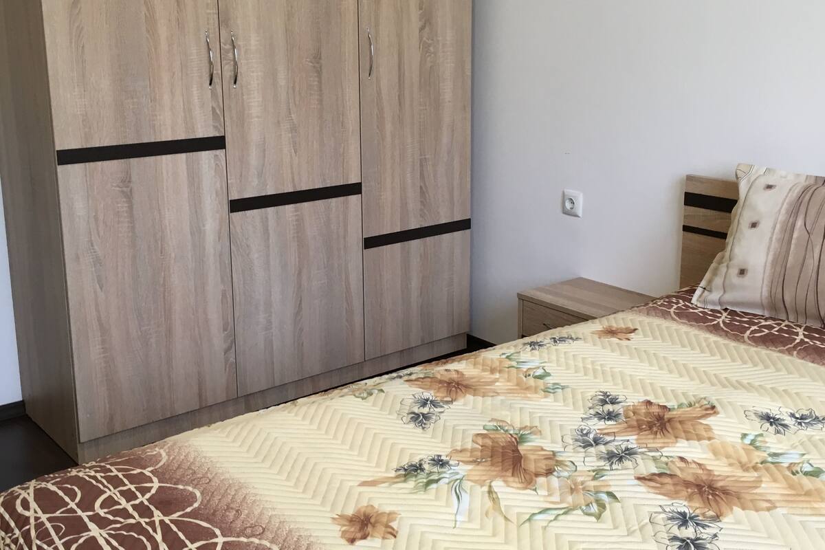 A bedroom with a bed, a wardrobe, and a bedside table.