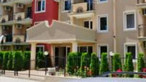 A multi-story hotel with balconies, a red corner building, and a covered entrance area. - VIP Zone Apartments (Sunny Beach)