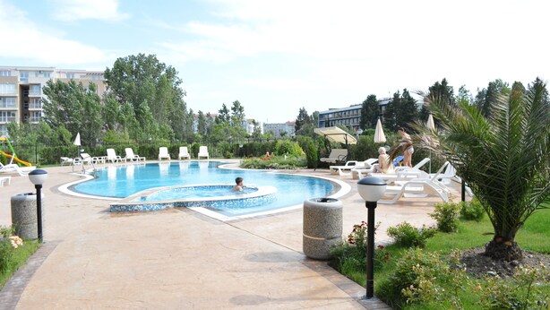 A swimming pool with lounge chairs and a palm tree. - VIP Zone Apartments (Sunny Beach)