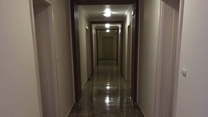 A hallway with a shiny marble floor, white walls, and doors on both sides. - VIP Zone Apartments (Sunny Beach)