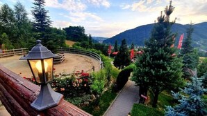 Un espacio al aire libre pintoresco con una terraza de madera, un farol y un sendero pavimentado que conduce a una zona circular con una valla.