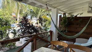 A covered outdoor area with a wooden table and chairs, a hammock, and various potted plants. - Casalina Garden Apartment Aruba (Noord)