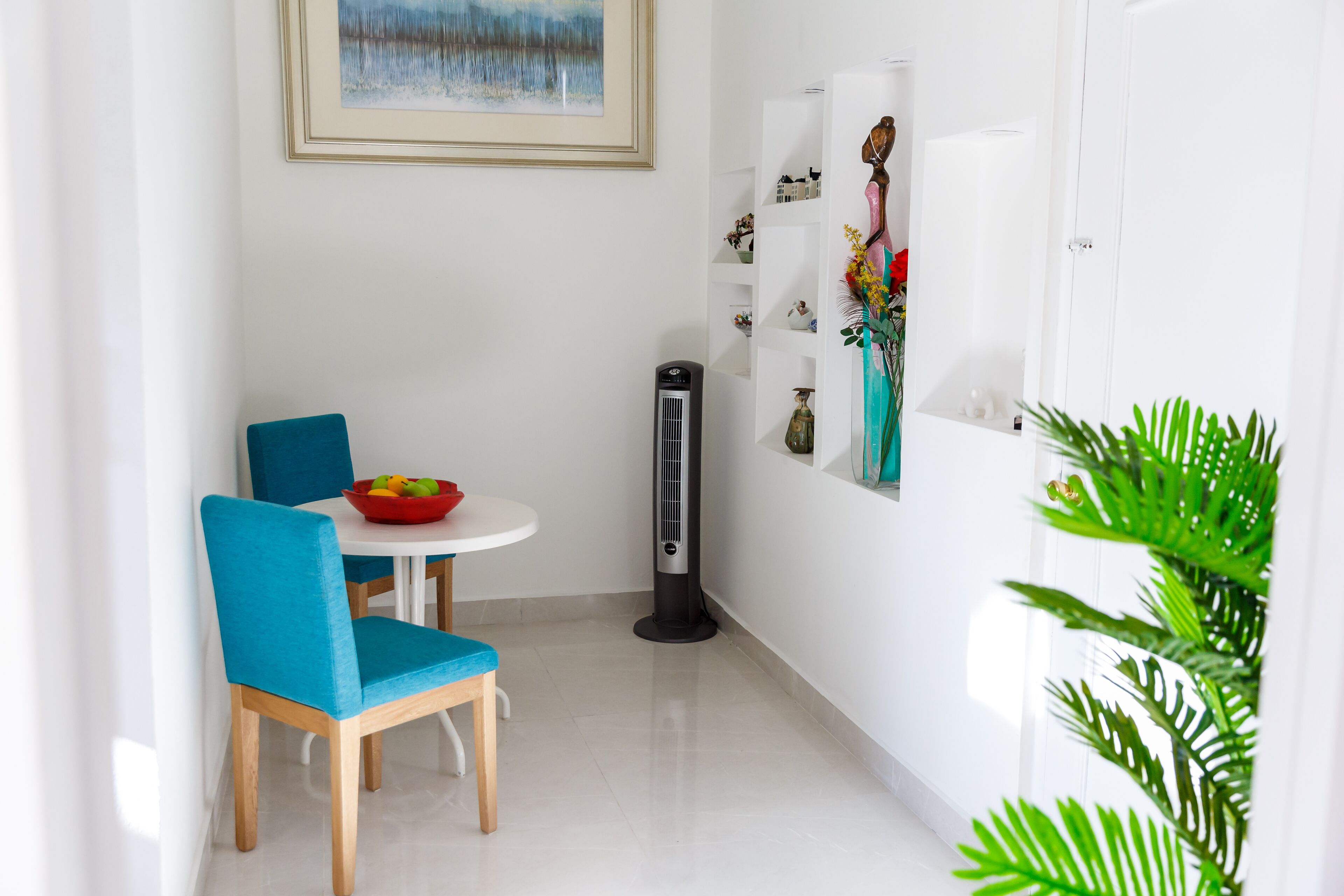 Un coin repas moderne avec une chaise bleue, une table blanche et un bol rouge.