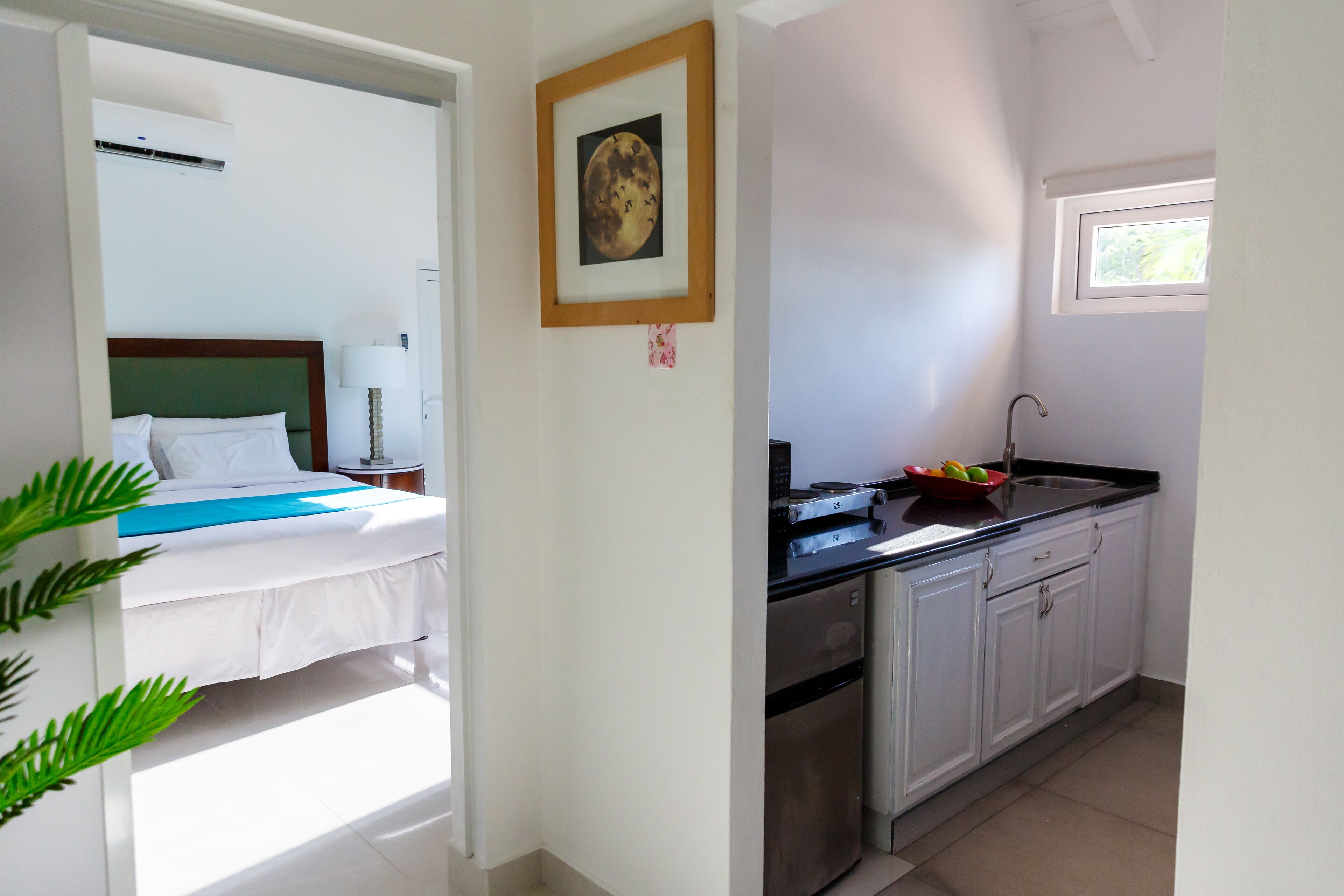 Quarto de hotel com uma cama, uma kitchenette pequena e uma janela.