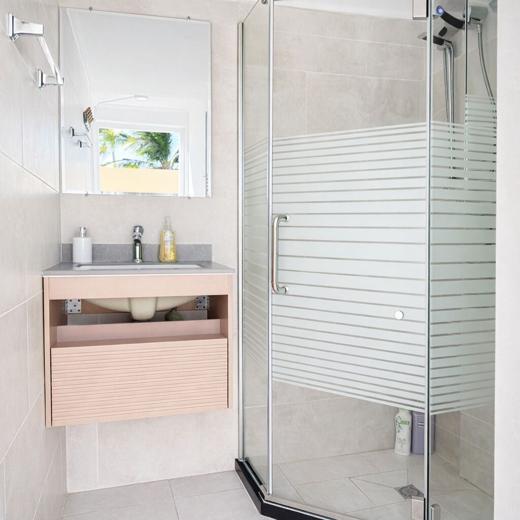 Un baño moderno con cabina de ducha de vidrio, un lavabo con espejo y un inodoro.