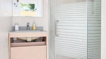 Un baño moderno con cabina de ducha de vidrio, un lavabo con espejo y un inodoro.