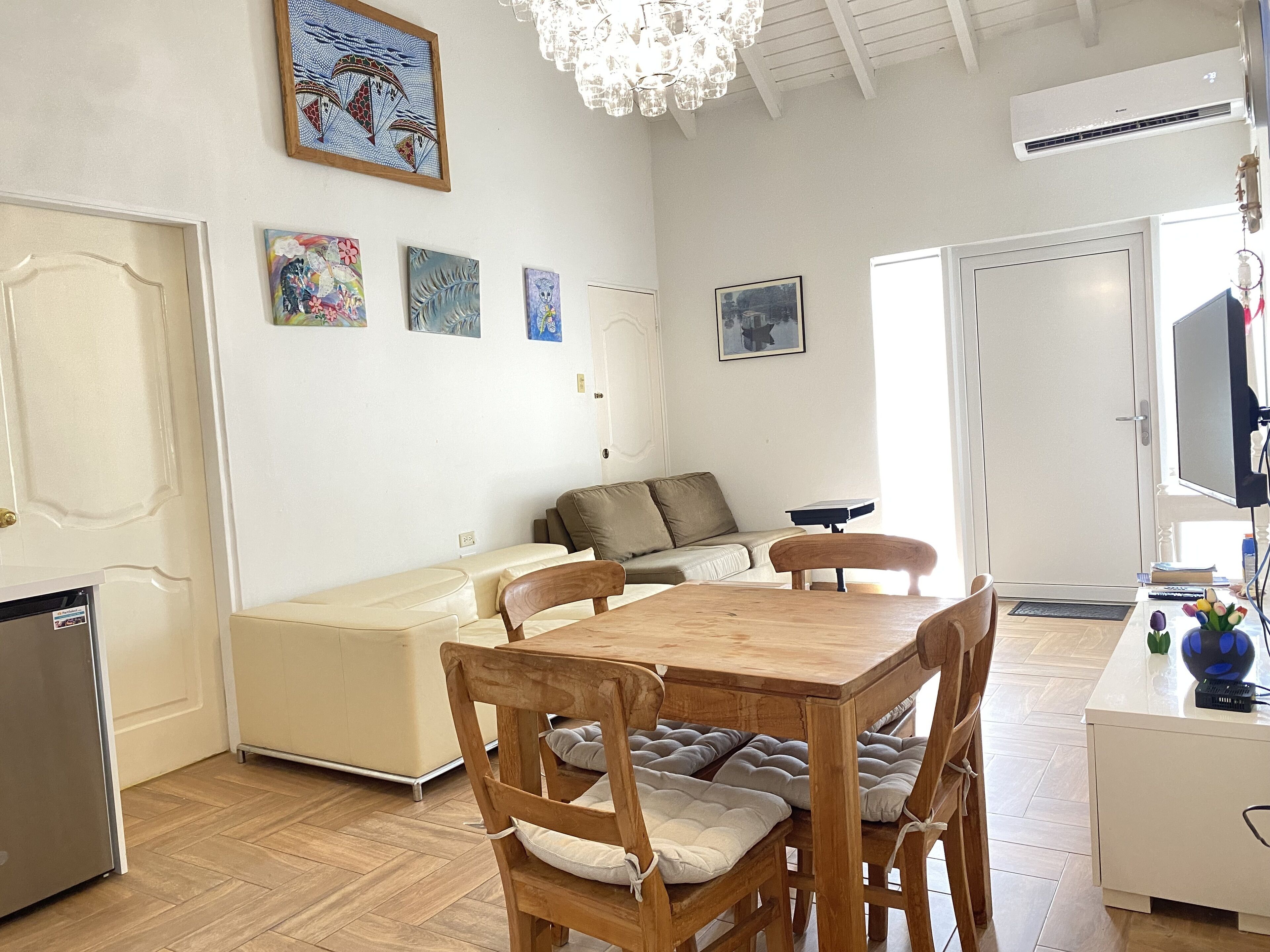 A cozy living area with a wooden dining table and chairs, a sofa, and a TV.