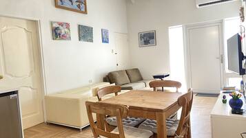 A cozy living area with a wooden dining table and chairs, a sofa, and a TV.
