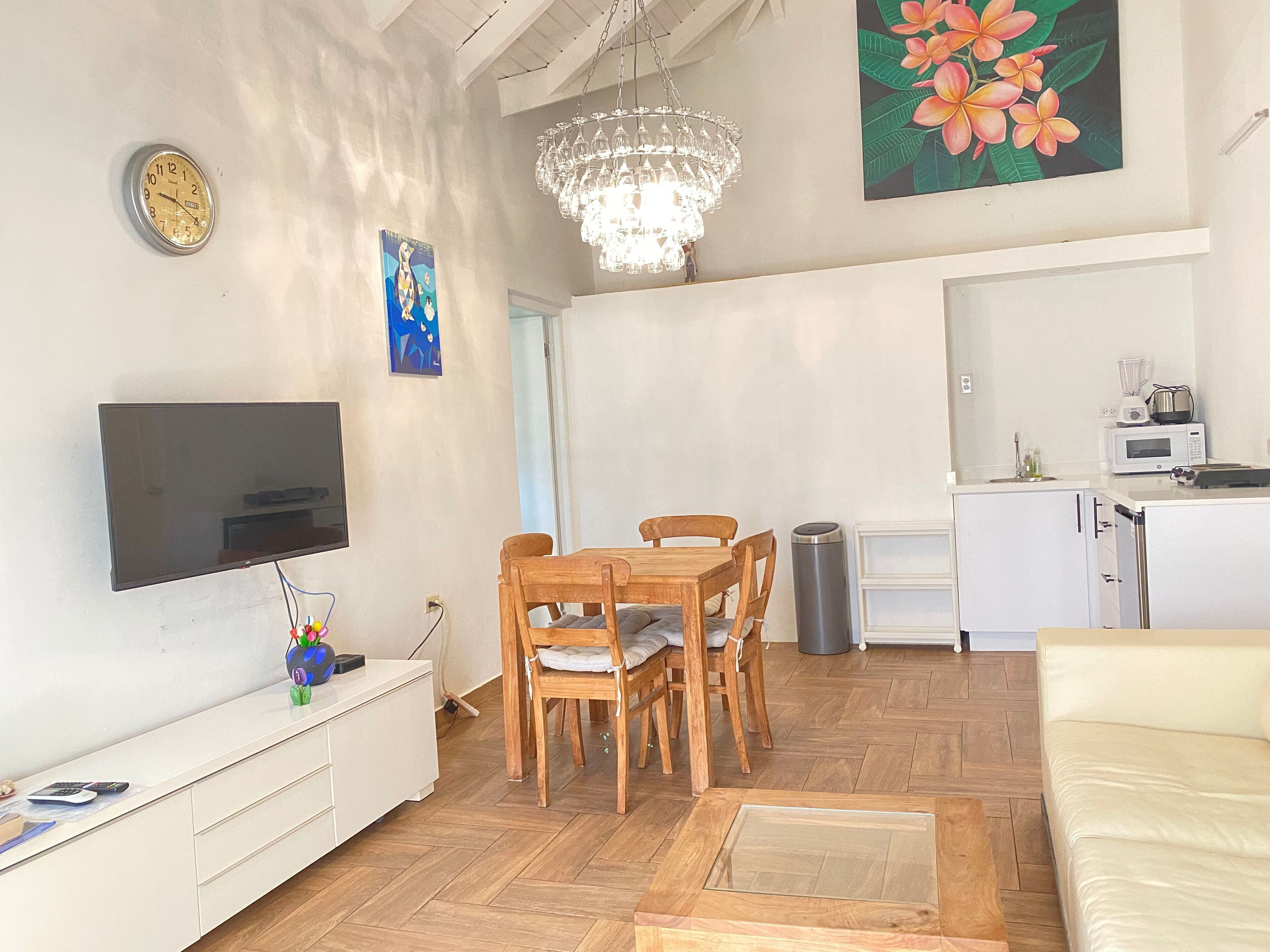 Un salon moderne doté d’un téléviseur à écran plat, d’une table à manger en bois et d’un lustre.