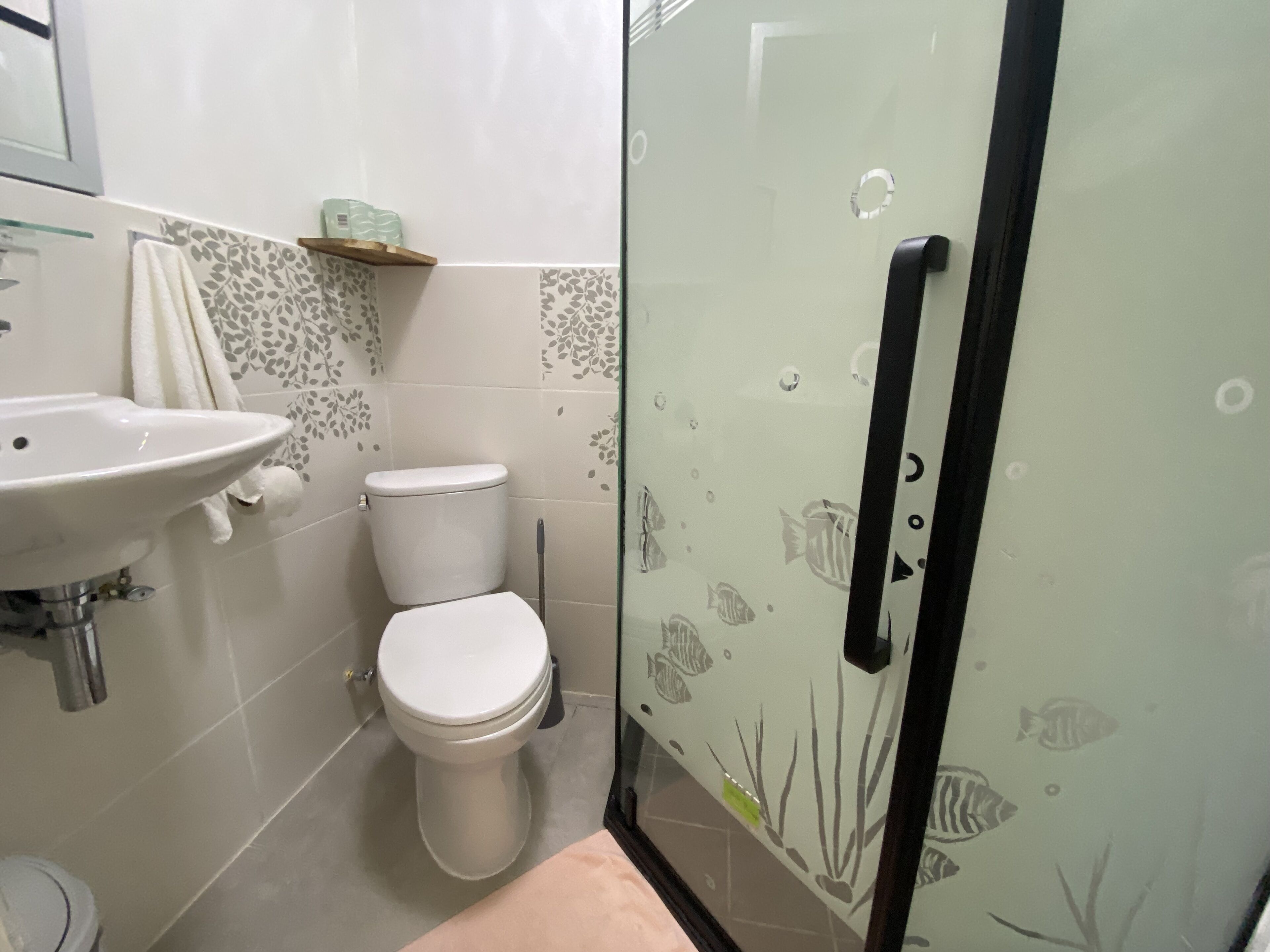 Un bagno con box doccia in vetro, lavandino bianco e un water.