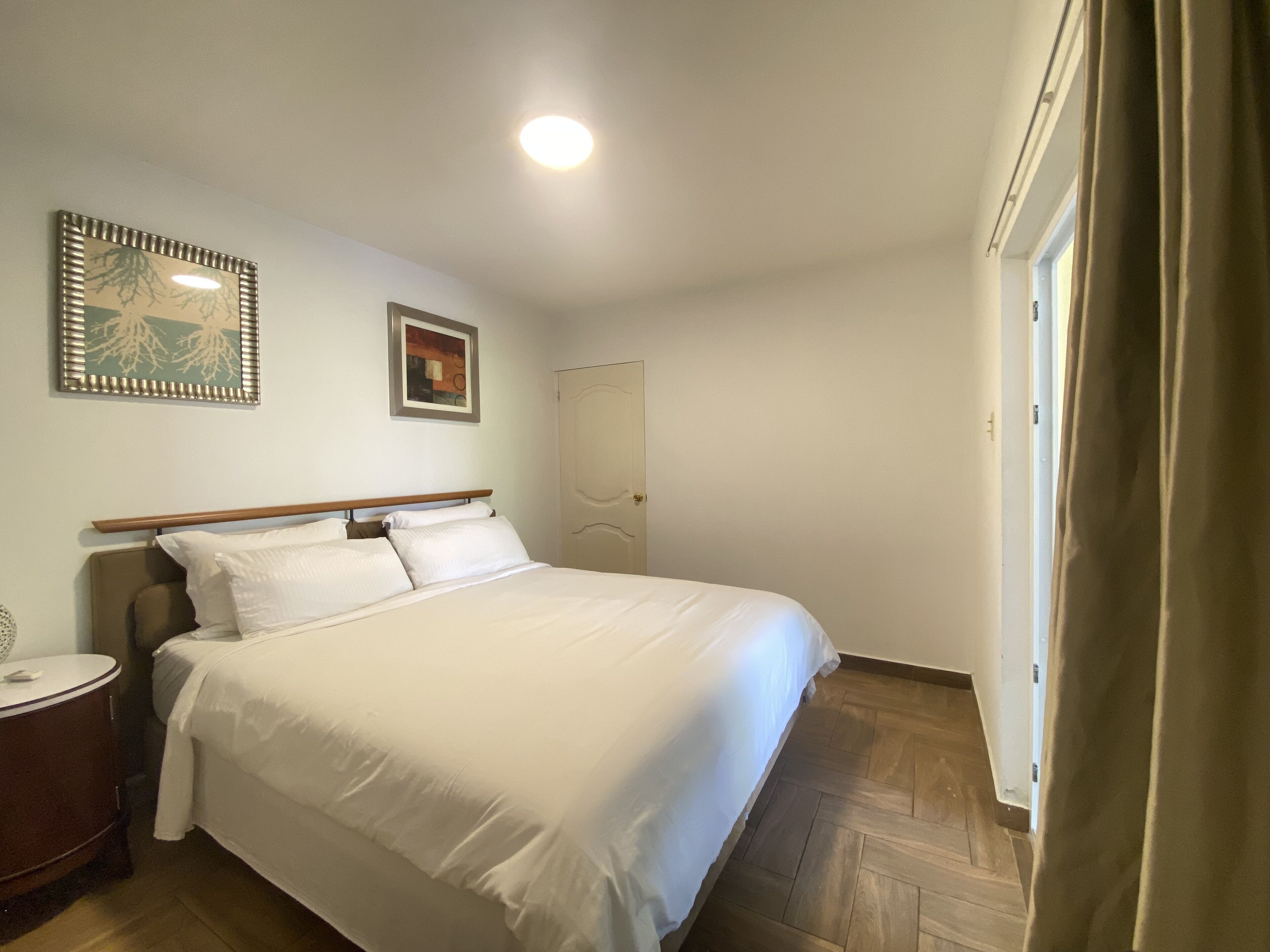 En pænt redt seng på et hotelværelse med et træhovedgærde, et sengebord og et natbord.