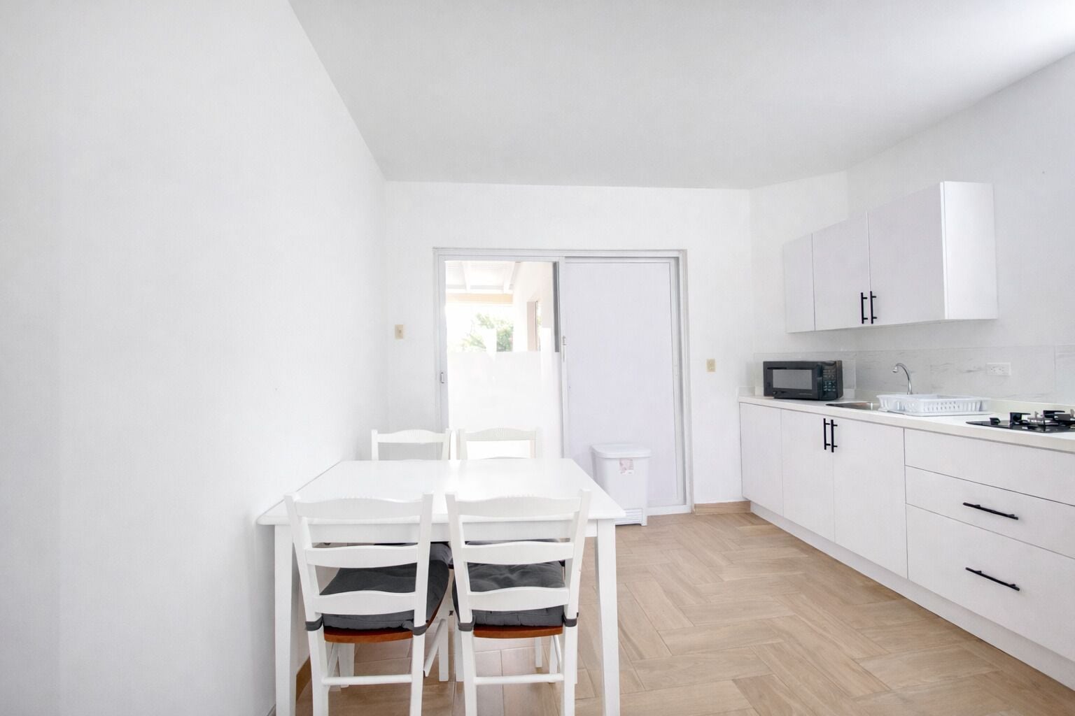 Una cocina moderna con armarios blancos, un microondas y un lavamanos.