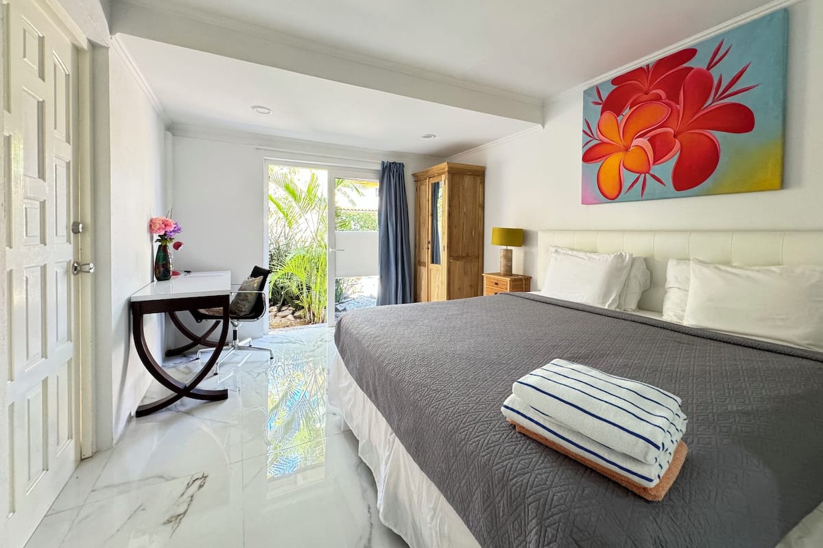 Une chambre d’hôtel avec un lit, un bureau, une chaise, une armoire et un tableau.
