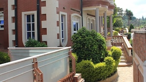 A multi-story building with a brick facade, large windows, and a balcony. - Diplomat Apartment Kacyiru (Kigali)
