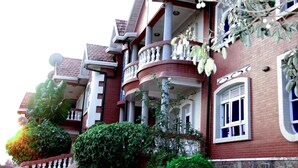A multi-story building with a brick facade, balconies with white railings, and a mix of windows and doors. - Diplomat Apartment Kacyiru (Kigali)