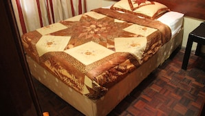A bed with a quilt featuring a star pattern and floral designs. - Diplomat Apartment Kacyiru (Kigali)
