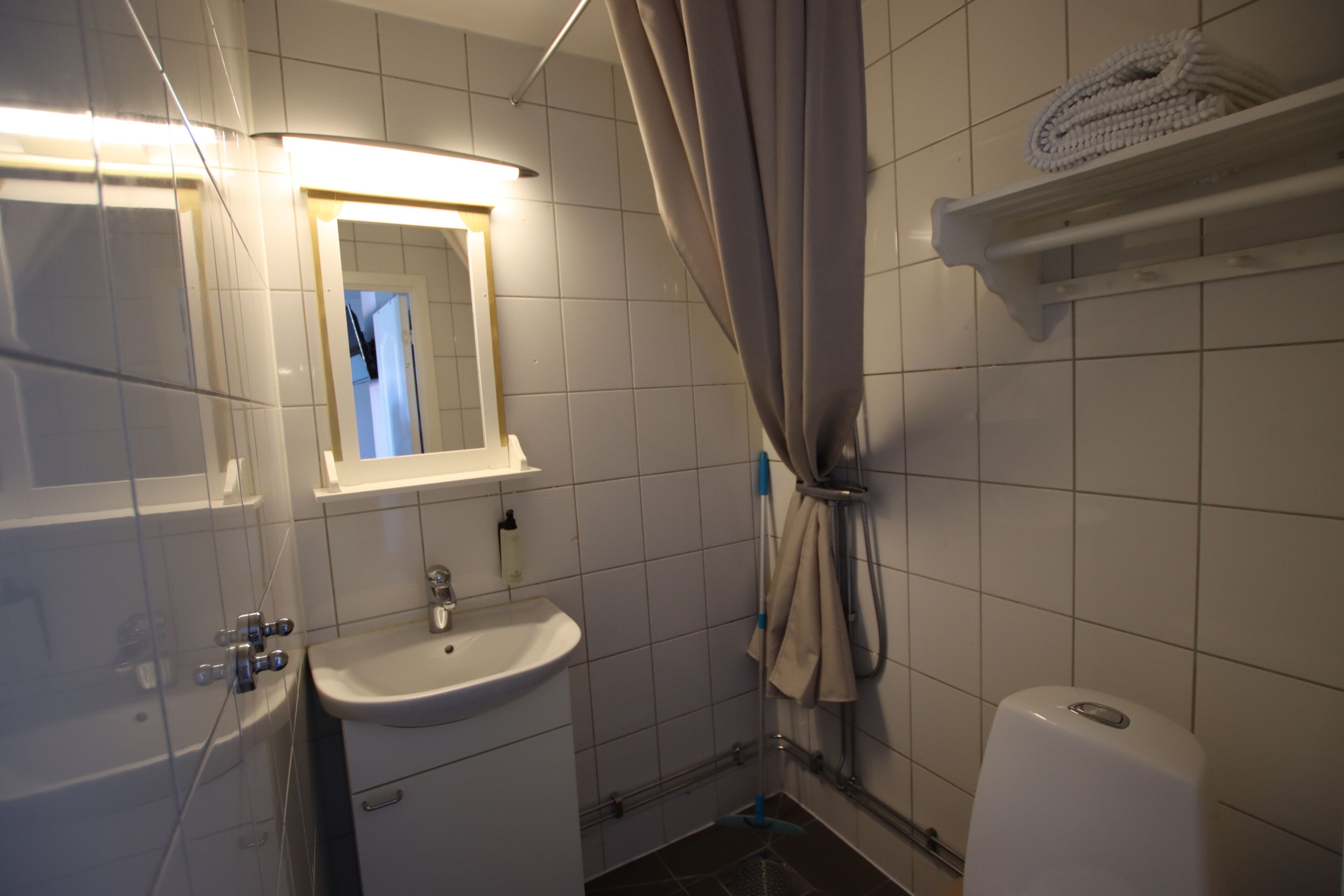 A bathroom with a sink, mirror, shower curtain, and toilet.