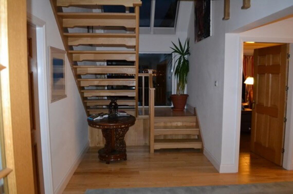 A staircase with a wooden railing, a potted plant, and a small table with a decorative base.