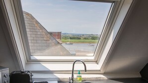 Eine Küche mit Blick auf ein Gewässer und Boote, inklusive Toaster, einer Spülmittelflasche und einem Spülbecken.