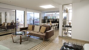 Uma sala de estar moderna com um sofá, mesa de centro e uma área de jantar com cadeiras e uma mesa.
