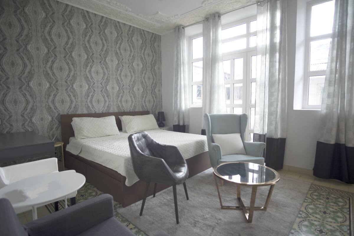 Ein Hotelzimmer mit einem großen Bett, einem Schreibtisch, einem Sessel und einem kleinen Tisch.