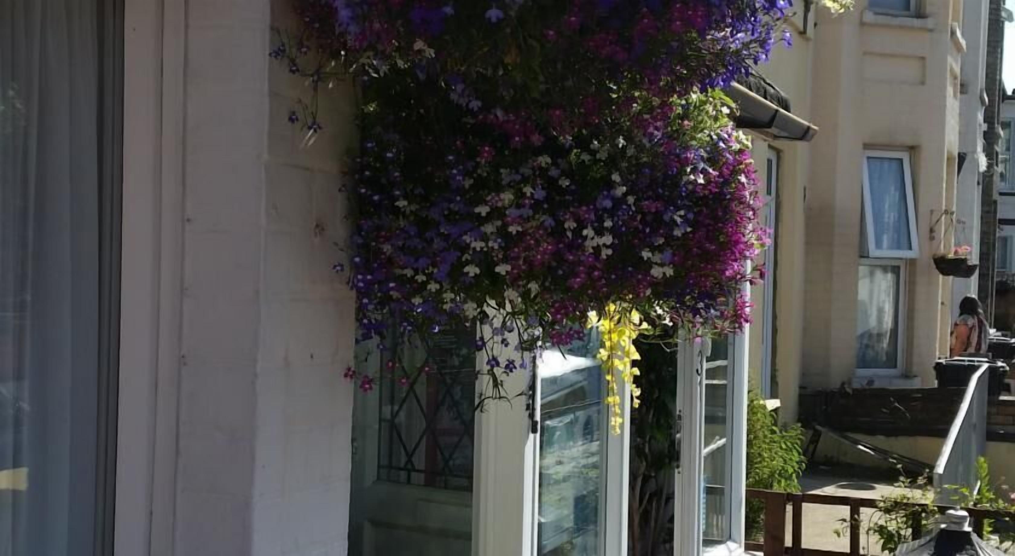 A building with a balcony adorned with hanging flower baskets.