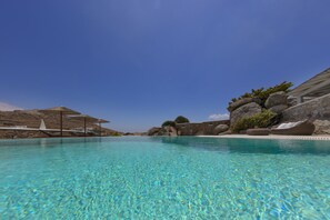 A clear blue pool with a stone wall and a rock formation on one side.